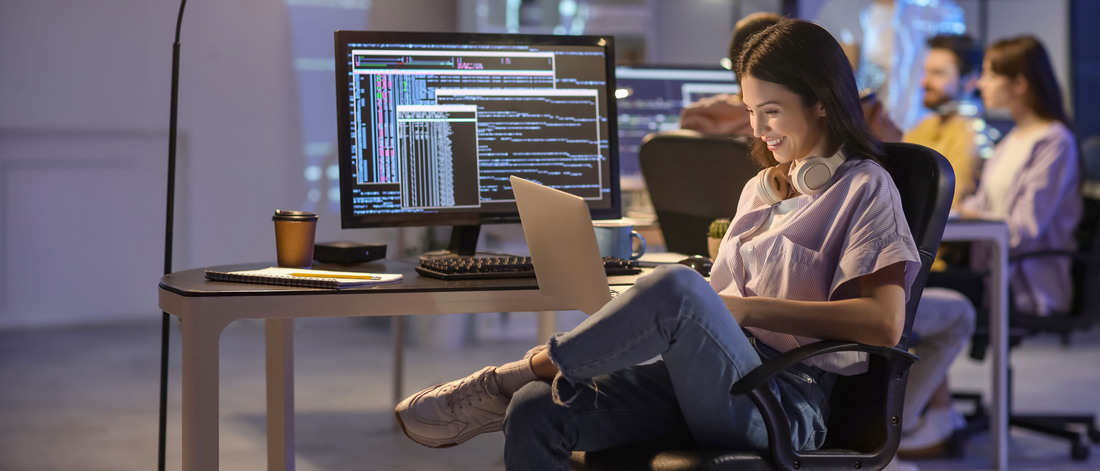 Female programmer working with laptop in office at night