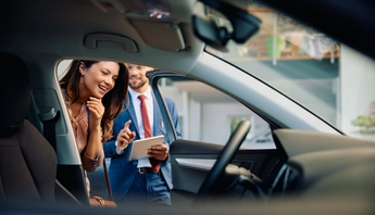 Happy woman buying new car in showroom