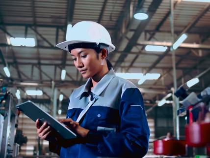 Engineer is using a tablet to check the machine's control system in a factory