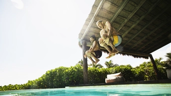 two men jumping into pool