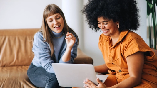 Cheerful young businesswomen using a laptop together in an office