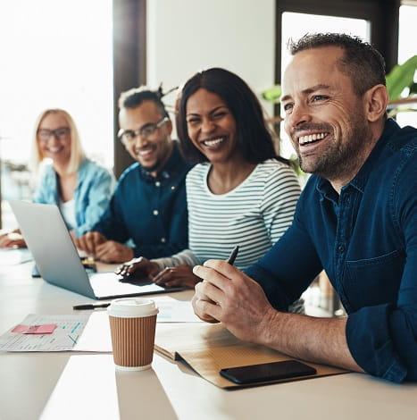 colleagues sitting at a long table smiling