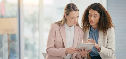 Tablet, teamwork and meeting with a business woman and colleague talking about an idea in their office together