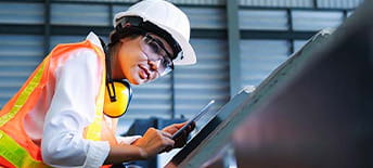 woman in hard hat sanding something metallic