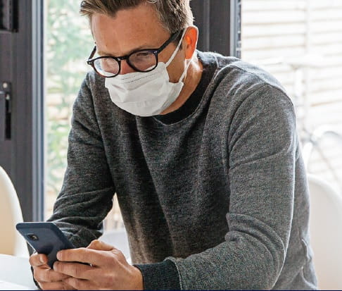 man wearing safety mask working on his mobile