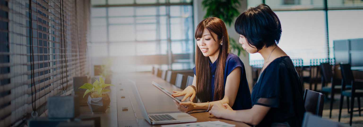 two women working together at a counter with laptop