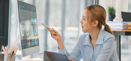 The female analyst utilizes a computer and a dashboard for business data analyze and a data management system with KPI. The concepts of technology, finance, operations, sales, and marketing.