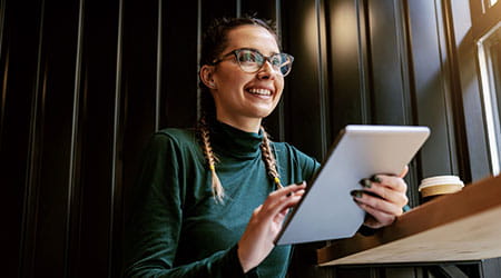 woman smiling while holding tablet