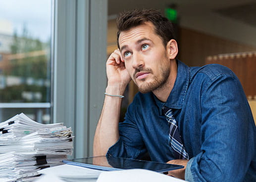 man sitting at desk with stack of papers