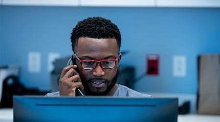 man on phone looking at laptop