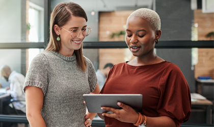 two women reviewing tablet in office setting