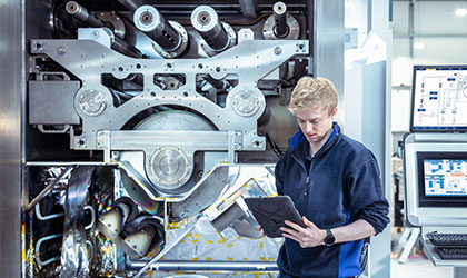 man working on tablet in front of manufacturing equipment