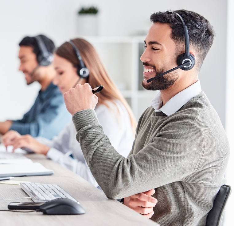 Man, call center and working in team office with headset, computer for online customer support, service or help. Businessman, employee and job in crm, telemarketing or communication help desk