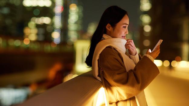 woman happily looking at mobile phone with lights behind her