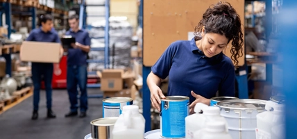 Employee organizing cans of paint at a distribution warehouse