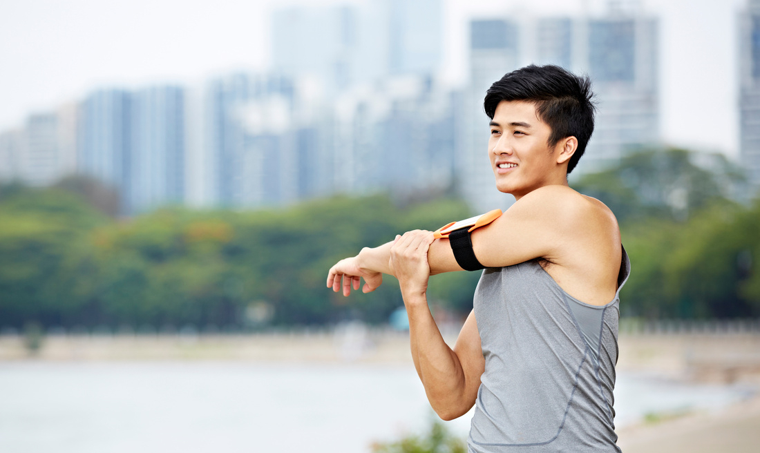 young asian jogger stretching arms before running