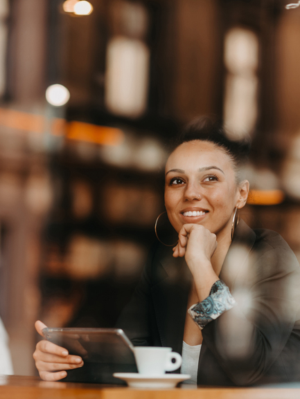 woman in a coffee shop drink coffee viewed through glass with reflections as they sit at a table chatting and laughing