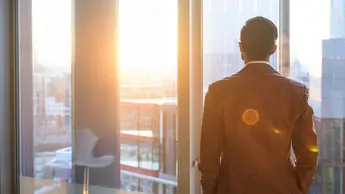 man looking out of window in city