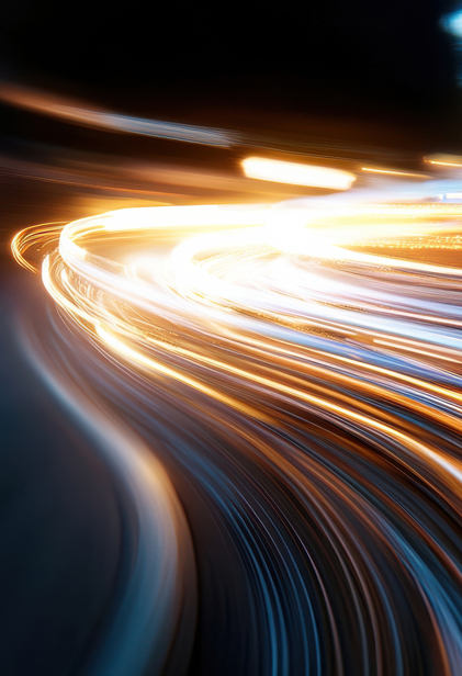 Dynamic streaks of light illuminate the urban nightscape, capturing the energy and movement of a bustling city as vehicles pass by, creating vibrant visual excitement.