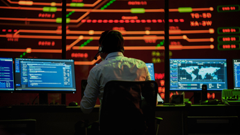 man wearing headset working in room of screens