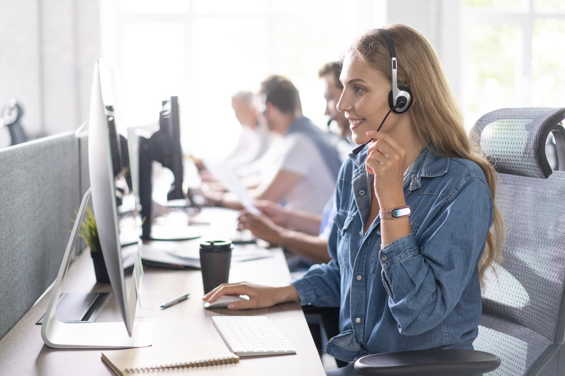 How can I help you? Beautiful call center workers in headphones are working at modern office