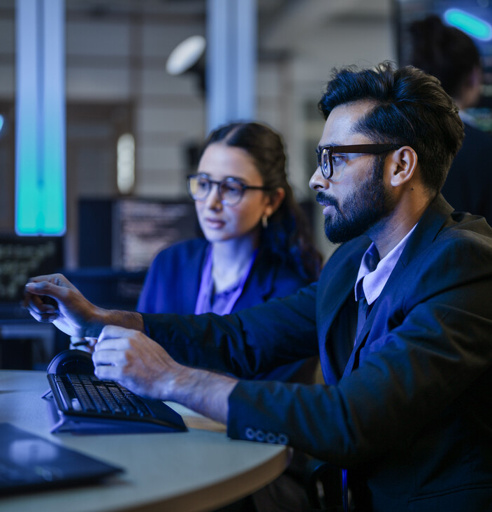 A diverse team of AI developers shares a successful moment in the office. A female programmer smiles as they review the positive results of a complex machine learning algorithm.