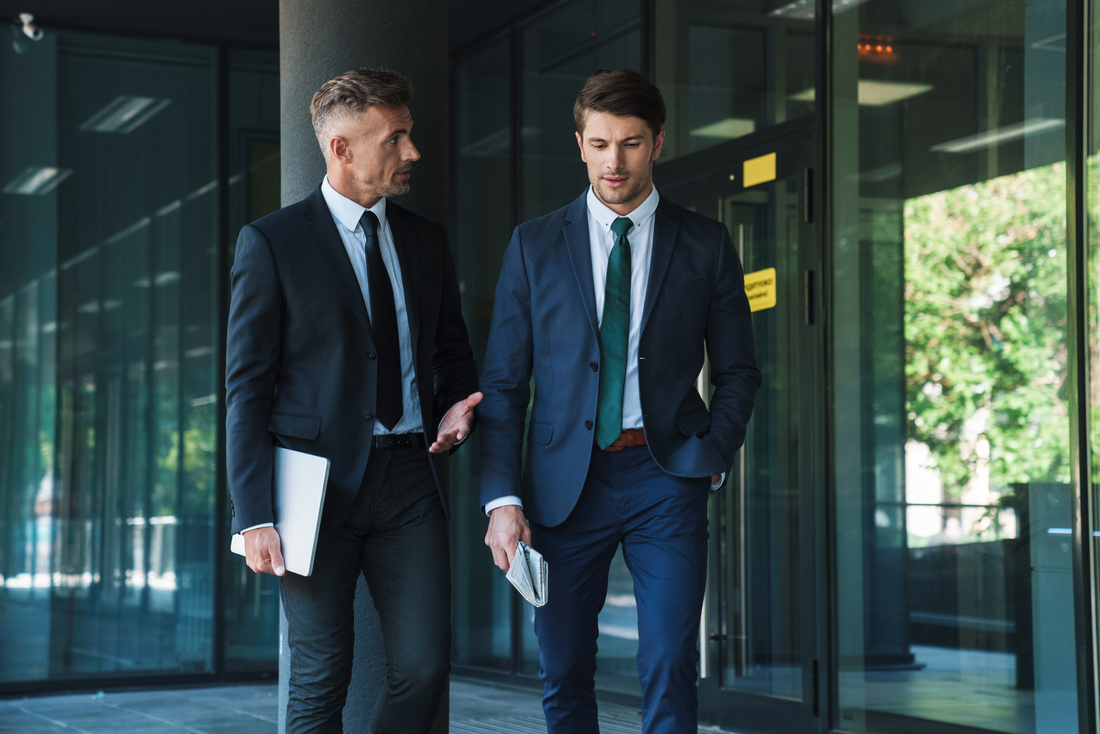 Portrait of two concentrated businessmen partners having conversation outside job center during working meeting