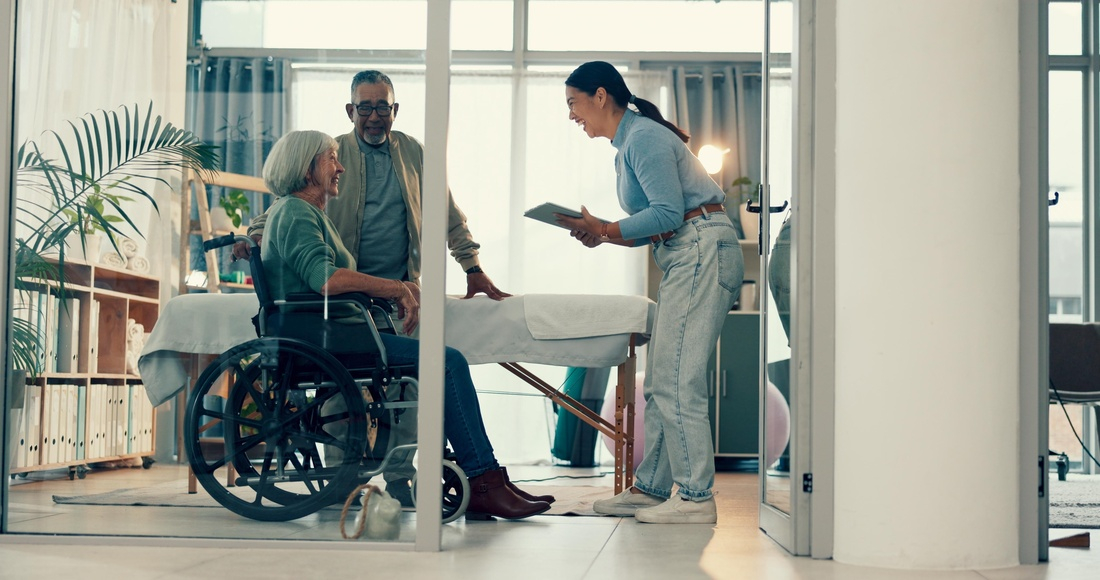 Senior, physiotherapy and couple with doctor and tablet for a consultation and person with disability. Rehabilitation, patient and woman speaking to a physiotherapist with tech for medical advice