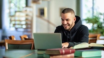 Male student using notebook and books and learning in the university library