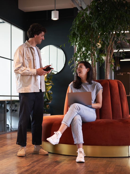 Young couple in work space for start up business have meeting in seating area of open plan office