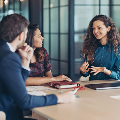 Smiling young businesswoman talking to her colleagues