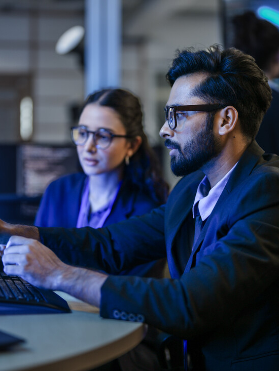 A diverse team of AI developers shares a successful moment in the office. A female programmer smiles as they review the positive results of a complex machine learning algorithm.