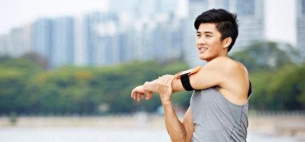 young asian jogger stretching arms before running