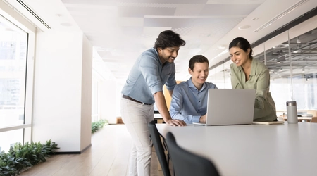 3 colleagues looking at laptop
