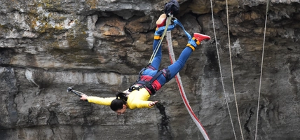 woman bungee jumping by cliff wall