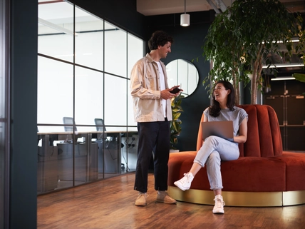 Young couple in work space for start up business have meeting in seating area of open plan office