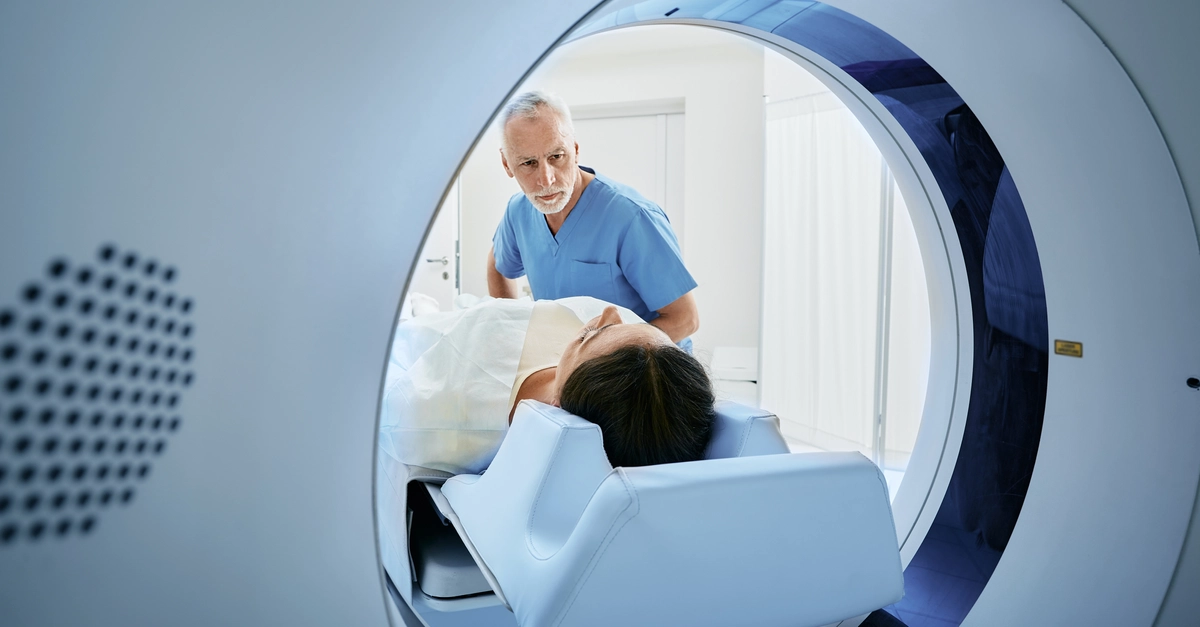 CT scan technologist overlooking patient in Computed Tomography scanner during preparation for procedure. Woman patient going into CT scanner
