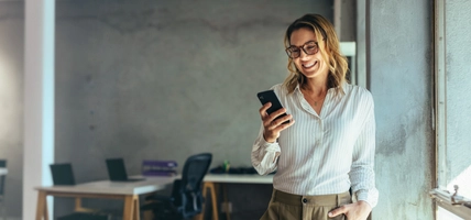 woman smiling while looking at mobile phone