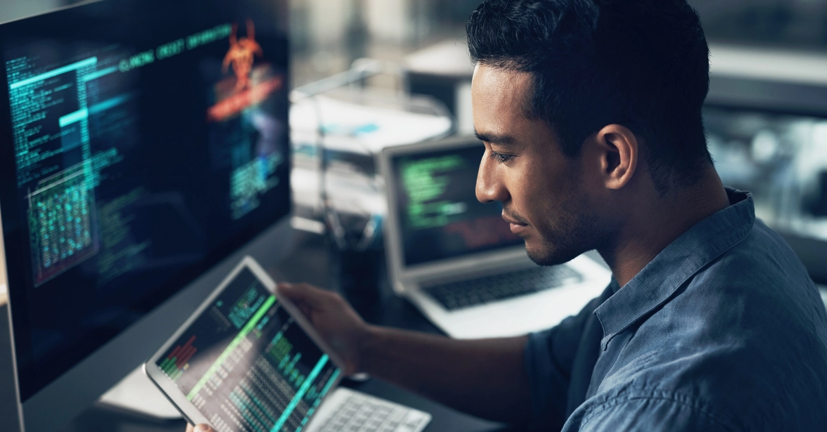 Programming, employee and man with a tablet, cyber security and computer in a modern office. Male person, programmer and coder with technology, coding and digital software with internet connection