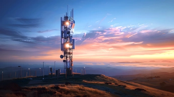 A modern cell tower with several dishes and antennas against the backdrop of blue sky at sunset. A telecommunication structure