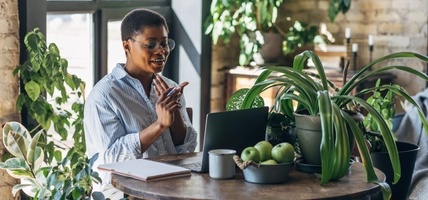 Cheerful healthy African American woman with laptop at home or in modern green office. Concept of video call, freelance job, studying remotely, learning, teaching languages, international education