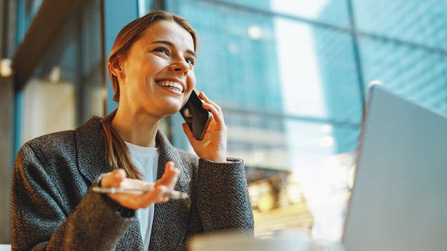 Young female freelancer talking with client and work on laptop in cafe. Distance work concept
