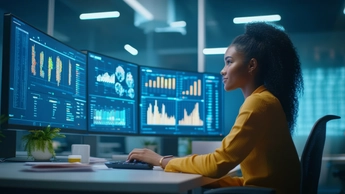 woman working at multiple screens of data