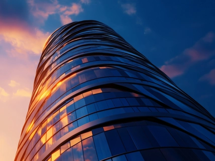 Modern glass skyscraper reflecting beautiful sunset skies with dynamic cloud formations in urban cityscape architecture.