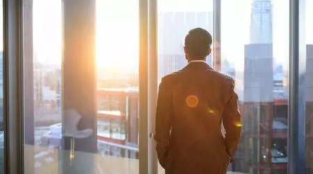 man looking out of window in city