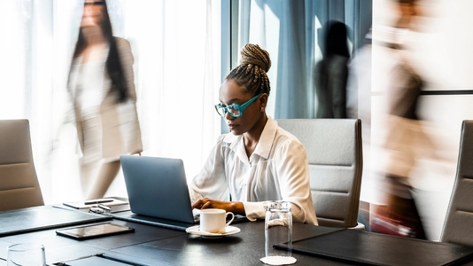 woman with blue glasses working at laptop