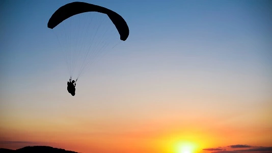 skydiver in sky at sunset