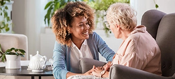 woman talking to older woman sitting in chair