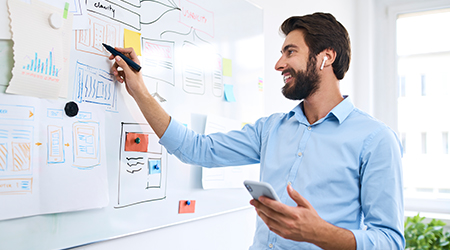 man working at whiteboard happily