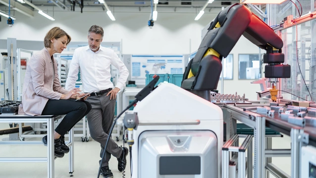 Businessman and businesswoman talking in a modern factory hall